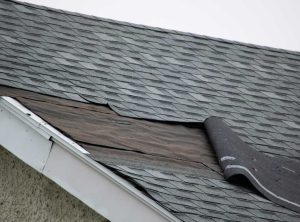A large portion of roof shingles blown off by a strong wind.